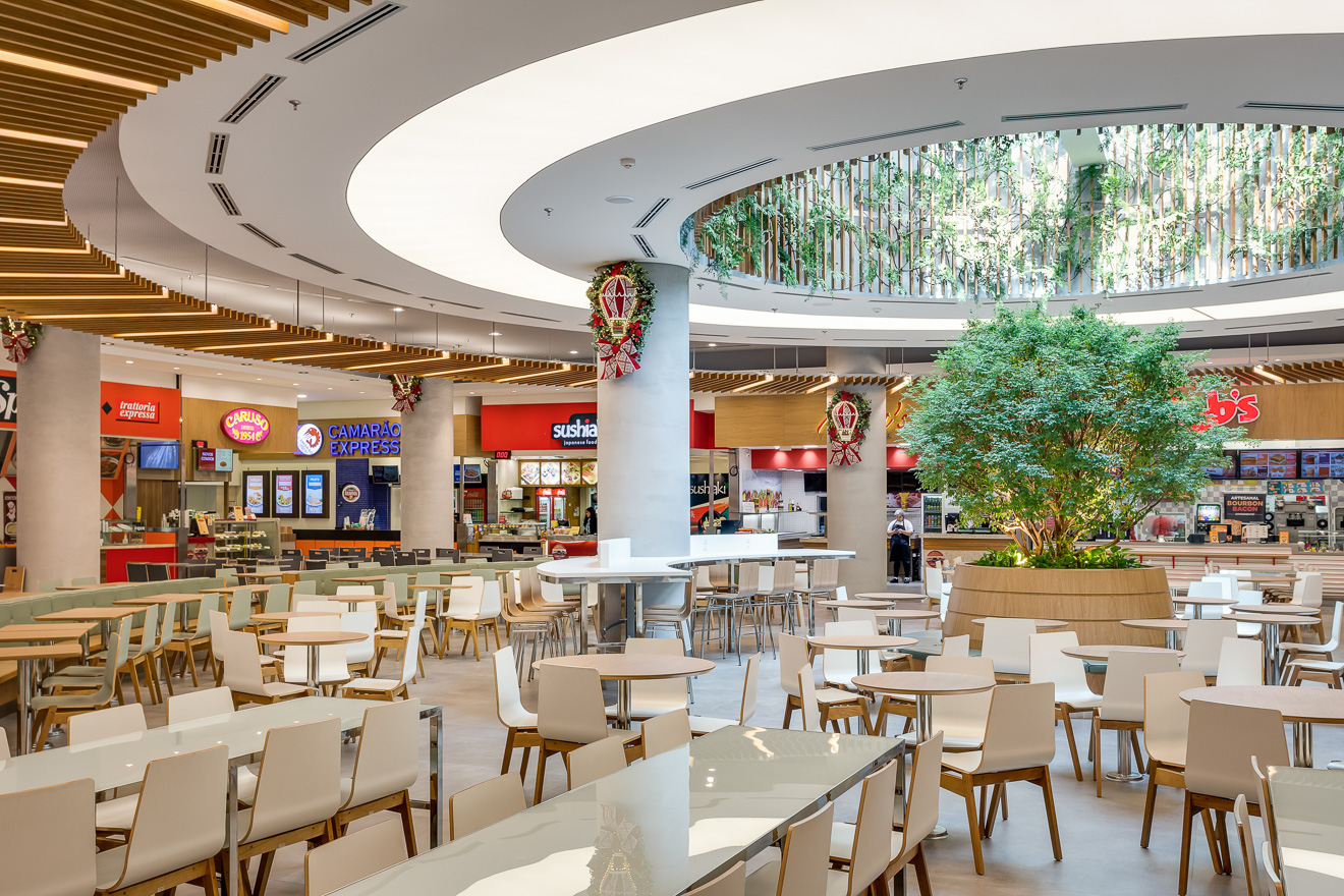 Shopping Mueller, Curitiba. Remodelação da praça de alimentação. A criação de três ambientes com identidades próprias, oferecem maior conforto e diferentes possibilidades de uso ao longo do dia. Destaque para o único ponto de entrada de luz natural que foi marcado com linhas curvas e uma grande jabuticabeira como ponto focal. Projeto premiado na Abrasce 2018 / Expansão e Revitalização. Projetado executado pela espaçonovo arquitetura, empresa especializada em arquitetura de varejo, sediada em São Paulo e qual a arquiteta Jovita Torrano é diretora e fundadora.