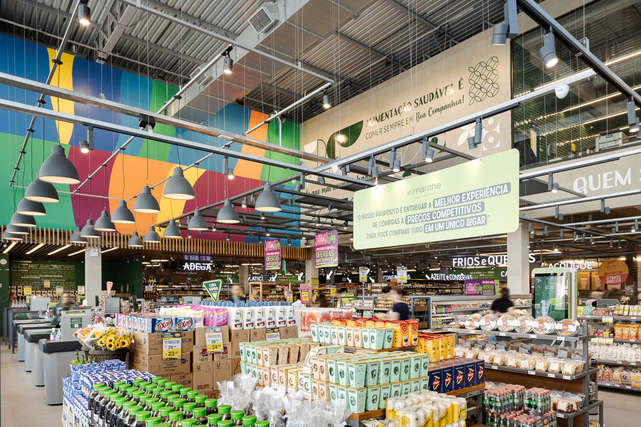 St Marche Supermercado, Tatuapé. Projetado executado pela espaçonovo arquitetura, empresa especializada em arquitetura de varejo, sediada em São Paulo e qual a arquiteta Jovita Torrano é diretora e fundadora. Projetamos a Edificação e todo o Interior desta unidade, numa esquina bastante valorizada, na Zona Leste da cidade de São Paulo. Através de grandes aberturas na fachada, podemos visualizar o interior da loja. Mesas externas instaladas num aconchegante deck voltado para a rua, permite degustar uma gostosa pizza de fermentação natural, enquanto integra a loja ao seu entorno.